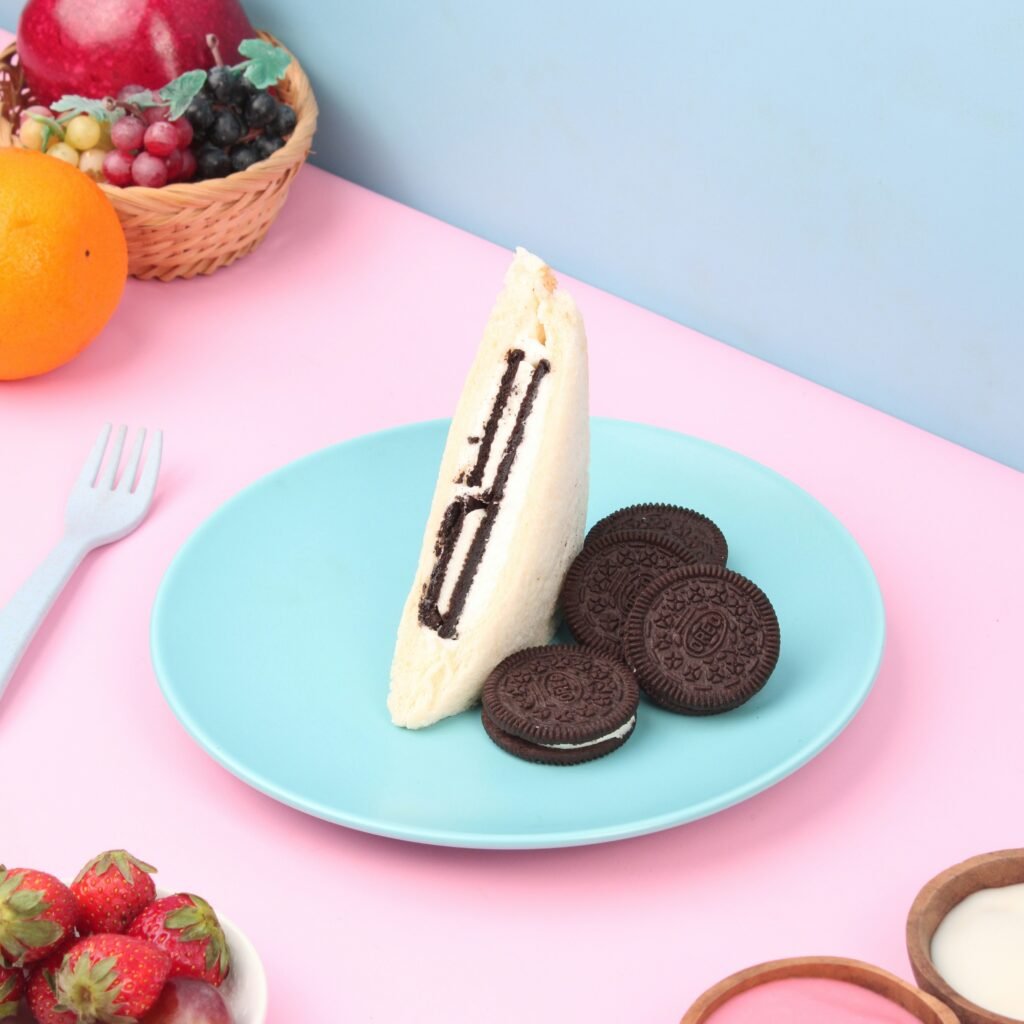 Soft Oreo cream sandwich dessert slice on a pastel plate with Oreo cookies and strawberries.