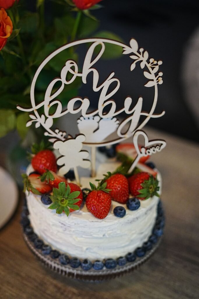 Elegant Oh Baby cake with strawberries, blueberries, white frosting, and baby shower cake topper.